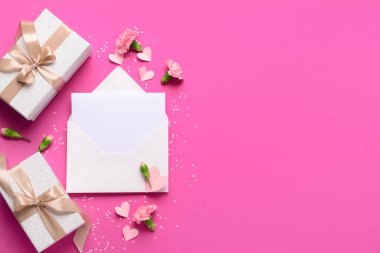 İçinde boş kart, hediye kutuları ve pembe arka planda karanfil çiçekleri olan bir zarf. Uluslararası Kadınlar Günü kutlamaları