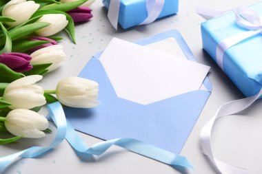 İçinde boş kart, hediye kutusu ve beyaz arka planda lale çiçekleri olan bir zarf. Uluslararası Kadınlar Günü kutlamaları