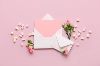 Boş kartlı zarflar ve pembe arka planda karanfil çiçekleri. Uluslararası Kadınlar Günü kutlamaları