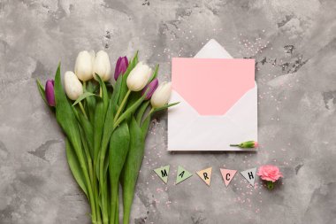 Üzerinde boş kart ve gri grunge arka planda lale çiçekleri olan zarf. Uluslararası Kadınlar Günü kutlamaları