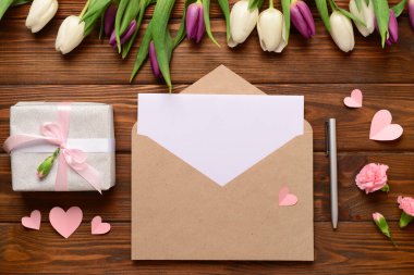 İçinde boş kart, hediye kutusu ve ahşap arka planda lale çiçekleri olan bir zarf. Uluslararası Kadınlar Günü kutlamaları