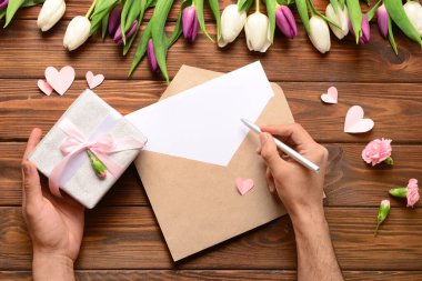 Zarflı erkek eller, boş kart ve tahta arka planda hediye kutusu. Uluslararası Kadınlar Günü kutlamaları