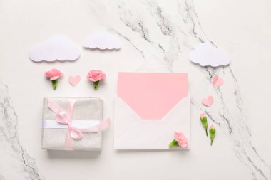İçinde boş kart, hediye kutusu ve beyaz grunge arka planda karanfil çiçekleri olan bir zarf. Uluslararası Kadınlar Günü kutlamaları