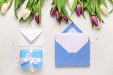 Boş kartlı zarflar, hediye kutusu ve beyaz arka planda lale çiçekleri. Uluslararası Kadınlar Günü kutlamaları