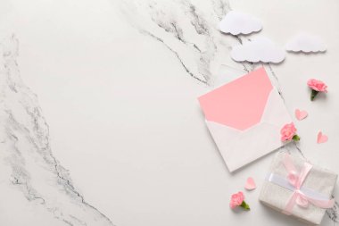 İçinde boş kart, hediye kutusu ve beyaz grunge arka planda karanfil çiçekleri olan bir zarf. Uluslararası Kadınlar Günü kutlamaları