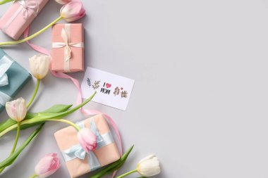 Kutlama kartı, hediye kutuları ve lale çiçekleri Anneler Günü kutlaması için arka planda.