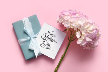 Mutlu Anneler Günü yazılı kart, pembe arka planda hediye kutusu ve ortanca çiçekleri