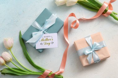 Mesajlı kart Mutlu Anneler Günü, hediye kutuları ve açık arkaplanda lale çiçekleri