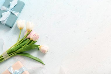 Anneler Günü için ışık arka planında hediye kutuları ve lale çiçekleri.