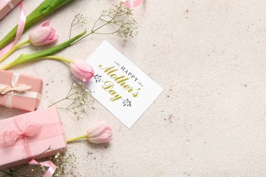 Mutlu Anneler Günü yazılı kart, hediye kutuları ve arka planda güzel çiçekler
