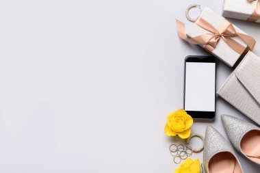 Modern cep telefonlu kompozisyon, şık kadın aksesuarları ve gri arka planda hediyeler