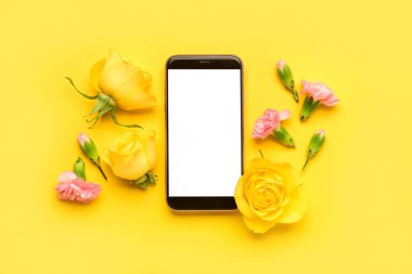 Modern cep telefonlu kompozisyon ve sarı arka planda güzel çiçekler.