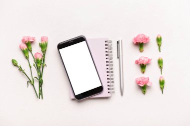 Modern cep telefonu, defter, kalem ve karanfil içeren kompozisyon