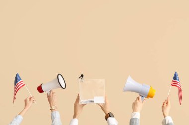 Oy sandığı olan eller, ABD bayrakları ve bej arka planda megafonlar. Seçim kavramı