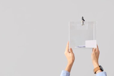 Beyaz arka planda oy sandığını tutan eller. Seçim kavramı