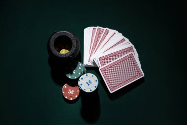 Poker fişleri, bozuk paralarla dolu tencere ve koyu yeşil arka planda kartlar. Aziz Patrick Günü kutlaması