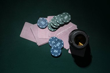 Poker fişleri, kartlar ve koyu yeşil arka planda bozuk paralar. Aziz Patrick Günü kutlaması