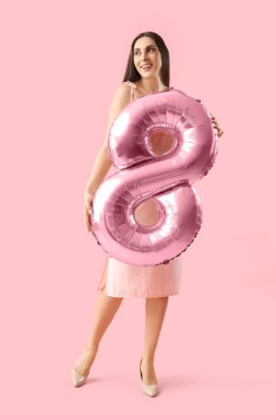 Young woman with balloon in shape of figure 8 on pink background. International Women's Day
