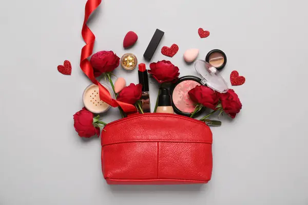 Cosmetic bag with make up products and red roses on white background. Valentine's day celebration