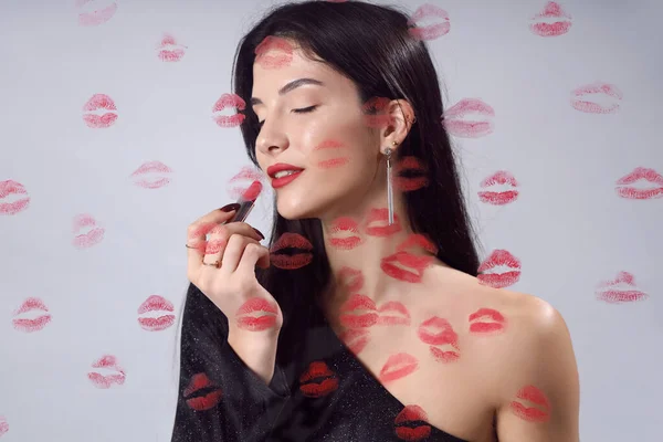 Young woman with lipstick and kiss marks on light background, closeup