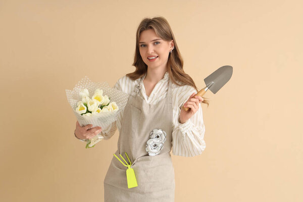 Young female gardener with bouquet of white tulips, shovel and balloon in shape of figure 8 on beige background. International Women's Day celebration
