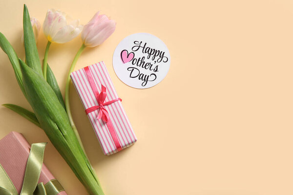 Карточка с текстом День Матери, подарочные коробки и цветы тюльпана на бежевом фоне