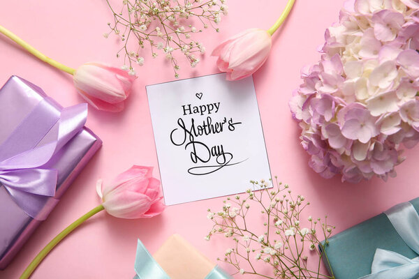 Карточка с текстом День Матери, подарочные коробки и красивые цветы на розовом фоне