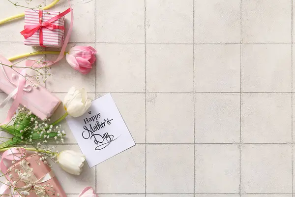 Mutlu Anneler Günü yazılı kart, hediye kutuları ve arka planda güzel çiçekler