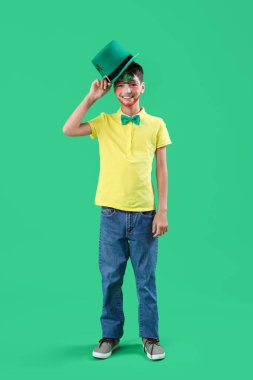 Yüzü boyalı ve yeşil arka planda cüce şapkası olan komik çocuk. Aziz Patrick Günü kutlaması