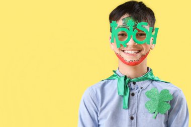 Yüzü boyalı ve sarı arka planda yenilik gözlüklü komik çocuk. Aziz Patrick Günü kutlaması