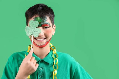 Yüzü boyalı ve yeşil arka planda yonca olan komik çocuk. Aziz Patrick Günü kutlaması