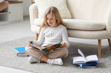 Evde yerde kitap okuyan küçük bir kız.
