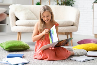 Sevimli küçük kız yerde evde otururken kitap okuma