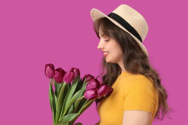 Mor arka planda güzel lalelerle dolu buketi olan güzel genç bir kadın.