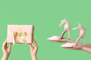 Yeşil arka planda şık topuklu ve hediye kutusu olan kadınlar.