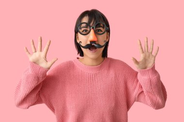 Pembe arka planda komik kılık değiştirmiş genç ve güzel bir kadın. 1 Nisan şakası