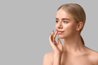 Gri arkaplanda güzel dudakları olan genç bir kadın.