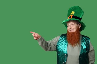 Kırmızı sakallı cüce şapkalı yaşlı kadın yeşil arka plandaki bir şeyi işaret ediyor. Aziz Patrick Günü kutlaması