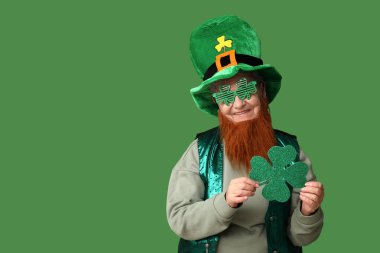 Yeşil arka planda yonca tutan kırmızı sakallı, cüce şapkalı, dekoratif gözlüklü yaşlı kadın. Aziz Patrick Günü kutlaması