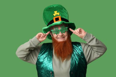 Yeşil arka planda kırmızı sakallı, cüce şapkalı ve dekoratif gözlüklü yaşlı kadın. Aziz Patrick Günü kutlaması