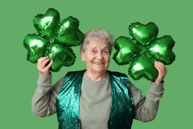 Yeşil arka planda yonca şeklinde balonları olan yaşlı bir kadın. Aziz Patrick Günü kutlaması