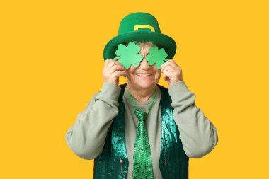 Sarı arka planda yonca olan cüce şapkalı yaşlı kadın. Aziz Patrick Günü kutlaması