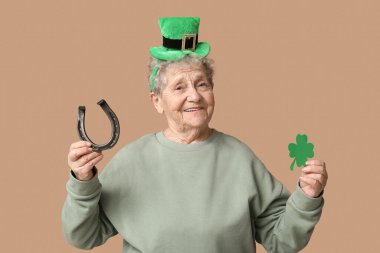 Kahverengi arka planda yonca ve at nalı olan cüce şapkalı yaşlı kadın. Aziz Patrick Günü kutlaması