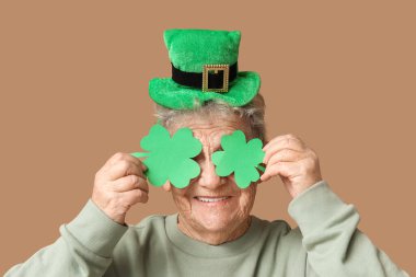 Kahverengi arka planda yonca olan cüce şapkalı yaşlı kadın. Aziz Patrick Günü kutlaması