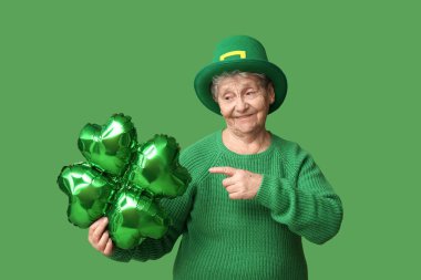 Yeşil arka planda yonca şeklinde balona bakan cüce şapkalı yaşlı kadın. Aziz Patrick Günü kutlaması