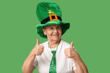 Yeşil arka planda baş parmak hareketi gösteren cüce şapkalı yaşlı kadın. Aziz Patrick Günü kutlaması