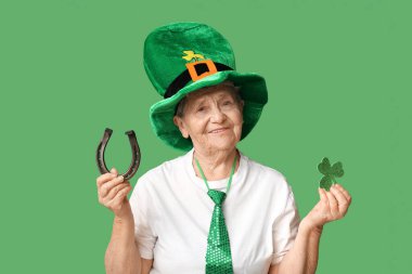 Yeşil arka planda at nalı ve yonca olan cüce şapkalı yaşlı kadın. Aziz Patrick Günü kutlaması