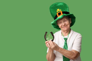 Yeşil arka planda at nalı ve yonca olan cüce şapkalı yaşlı kadın. Aziz Patrick Günü kutlaması