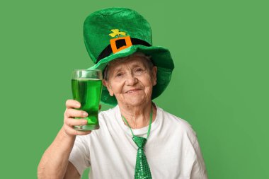 Yeşil arka planda bir bardak birayla cüce şapkalı yaşlı kadın. Aziz Patrick Günü kutlaması