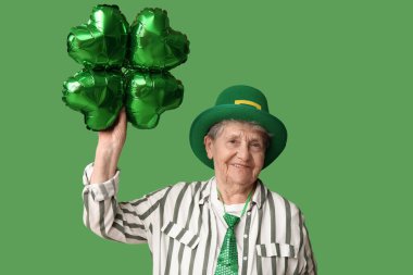 Yeşil arka planda yonca şeklinde hava balonu olan cüce şapkalı yaşlı kadın. Aziz Patrick Günü kutlaması